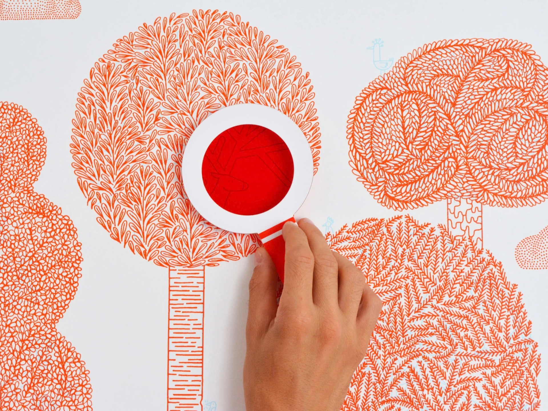 Une main manipule une loupe au-dessus d'un dessin